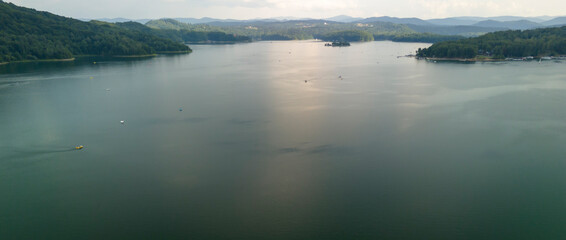 Serene view of a tranquil lake surrounded by forested hills, capturing the essence of nature and outdoor beauty.