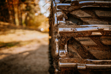 Close-up of a forestry harvester’s muddy tire tread with metal cleats, emphasizing rugged terrain...