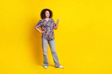 Full body photo of pretty young girl point look empty space wear trendy colorful outfit isolated on yellow color background