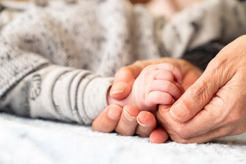 A baby's hand is being held by a parent. The concept of family love and protection