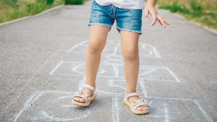 Close-up of a girl feet and hopscotch painted on the asphalt. A child plays hopscotch on an outdoor...