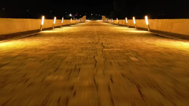 Aerial high angle footage of a 150 years old stone masonry bridge illuminated on a dark night. Drone shot of Master Kolyo Fitcheto's bridge at Byala village over the river of Yantra in Bulgaria.
