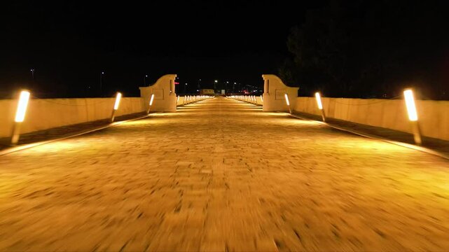 Aerial high angle footage of a 150 years old stone masonry bridge illuminated on a dark night. Drone shot of Master Kolyo Fitcheto's bridge at Byala village over the river of Yantra in Bulgaria.
