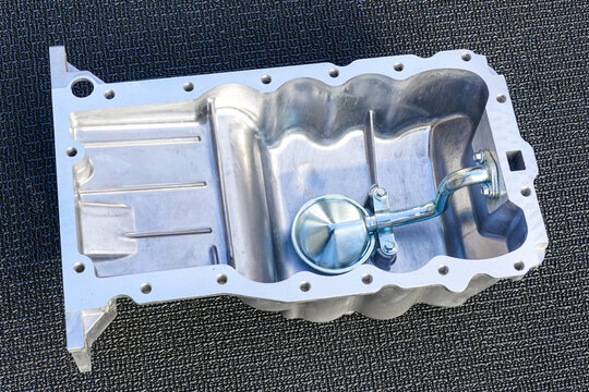 Passenger car engine new aluminum oil sump with oil receiver tube on gray background, new crankcase