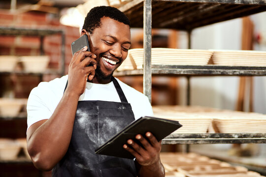 Phone call, baker and laughing black man on tablet for online order, talking or cooking. Communication, smile or chef in bakery on technology for food production, bread manufacturing or startup sales - Powered by Adobe