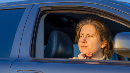 A Thoughtful Woman Gazes out of a Car Window During Sunset, Reflecting on Life and Experiences in a Serene Moment