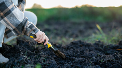 A Gardener Cultivates the Rich Soil on a Sunny Evening, Preparing for Planting in a Lush Green Field