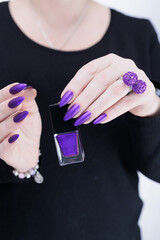 Female hands with long nails and dark purple manicure 