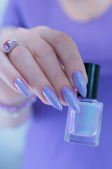 Female hand with long nails and a lilac and blue nail polish