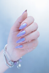 Female hand with long nails and a lilac and blue nail polish