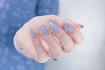 Female hand with long nails and a lilac blue nail polish