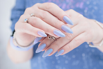 Woman's beautiful hand with long nails and light blue and lilac manicure	