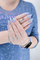 Woman hand with long nails manicure and light lilac and blue nail polish