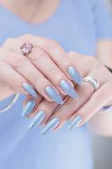 Woman hand with long nails manicure and light lilac and blue nail polish