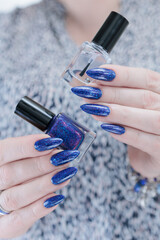 Woman's beautiful hand with long nails and bright blue purple manicure