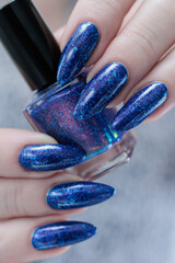Woman's beautiful hand with long nails and bright blue purple manicure