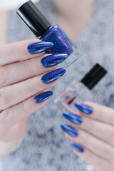Woman's beautiful hand with long nails and bright blue purple manicure