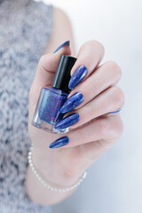 Woman's beautiful hand with long nails and bright blue purple manicure