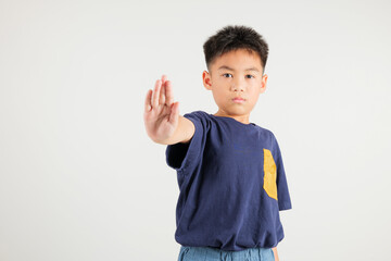 Asian portrait cute young kid boy smiling doing show stop sign gesture with palm of hand but...