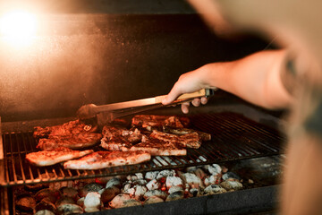 Hands, meat and flames for barbecue, event and celebration on weekend or holiday with fireplace. Person, cooking and bbq as food for nutrition, dinner and beef on grill in party, reunion or backyard