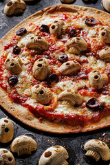 Close-up view of express pizza on tortilla. Halloween pizza with mushroom skulls, tomato sauce and mozzarella cheese. Idea for a Halloween party.