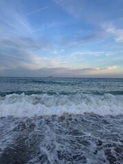 A quiet beach with gentle waves rolling onto the shore under a soft, twilight sky. The calm ocean and dim, fading light create a serene and peaceful atmosphere, ideal for unwinding and relaxation.