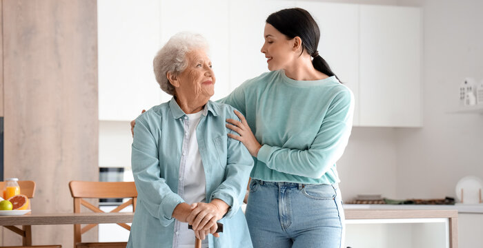 Senior woman with walking stick and her daughter in kitchen