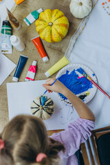 Children and adults painting pumpkins for Halloween, enjoying a fun and creative activity together.
