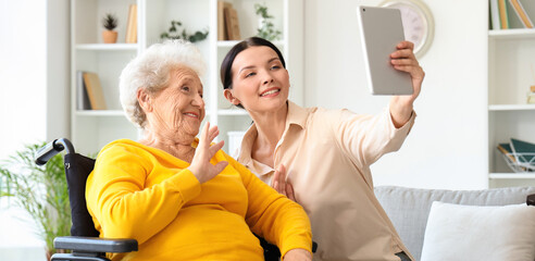 Senior woman in wheelchair with her daughter video chatting at home