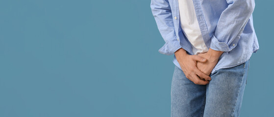 Young man with prostate problem on blue background, closeup. Cancer awareness concept