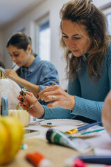 Fototapeta premium Children and adults painting pumpkins for Halloween, enjoying a fun and creative activity together.