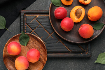 Plates with sweet apricots on black background