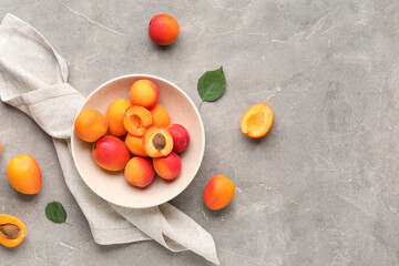 Bowl with sweet apricots on grey background