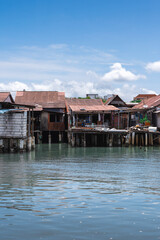 Fototapeta premium Photograph of traditional floating houses in George Town, Malaysia, captured on a bright, clear day with a vibrant blue sky. The serene scene showcases the unique waterfront architecture.