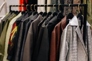 Autumnal stylish leather jackets hanging in a row on hangers in a fashion luxury boutique