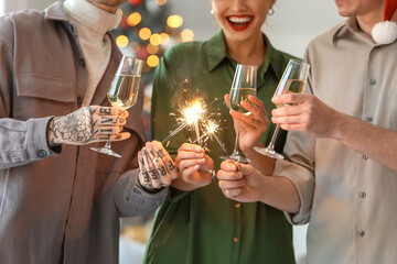 Young friends with champagne and sparklers celebrating New Year at home party, closeup