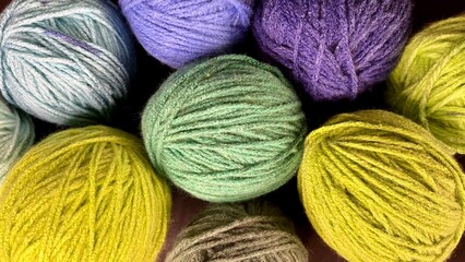 close up round skeins of yarn for knitting green blue purple light blue brown colors