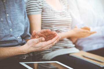 Business people clapping at meeting or conference, close-up of hands. Group of unknown businessmen and women in sunny office