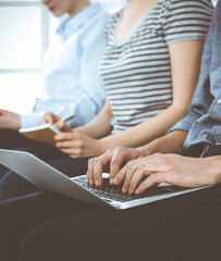 Group of casual dressed business people working at meeting or conference, close-up of hands. Businessman using laptop computer. Teamwork or coaching concept