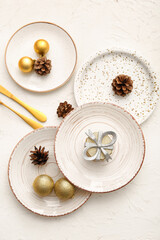 Beautiful table setting with Christmas balls, cones and gift box on white background