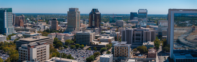 Aerial view of Sacramento, California, featuring modern skyscrapers like Wells Fargo Center and US Bank Tower, with lush greenery in the background.