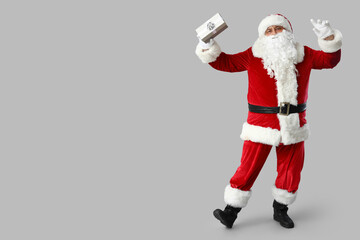 Dancing Santa Claus with gift box on grey background