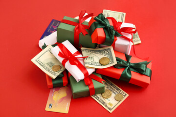 Christmas gift boxes with money and credit cards on red background