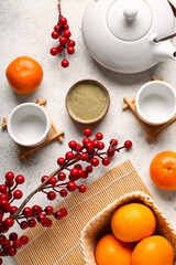Teapot with matcha tea, mandarins and berries on white grunge background. New Year celebration