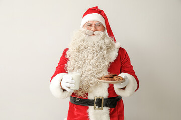 Santa Claus with glass of milk and tasty cookies on white background