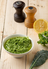 Vegan dipping Pesto Paste in a white ceramic bowl Kale and basil and cut lemon