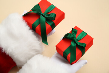 Santa Claus with gift boxes on beige background