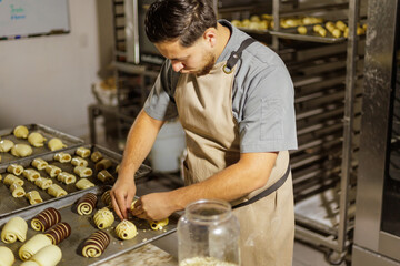 In the bustling bakery, a Mexican baker carefully tops the pan dulce with almonds, making sure each piece gets a perfect amount for added texture and flavor