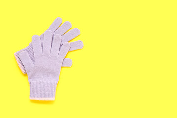 Pair of warm gloves on yellow background