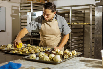 A Mexican baker, in a bakery setting, carefully executes detailed steps in pan dulce preparation, highlighting their skill and precision in traditional baking.